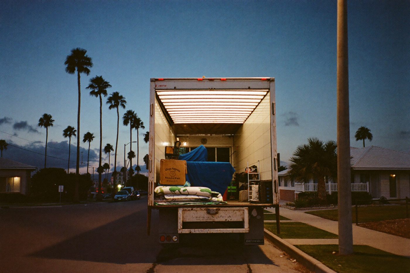 Open box truck on a palm-lined South Florida street at dusk